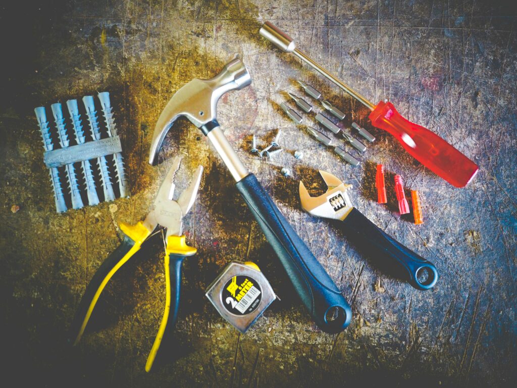 Collection of hand tools including hammer, screwdriver, and pliers in a workshop setting.